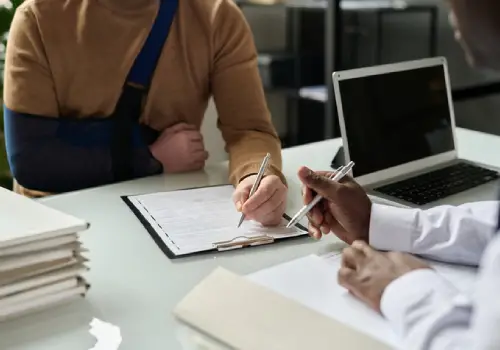 A man with an injury signing legal paperwork with a personal injury attorney in Augusta GA